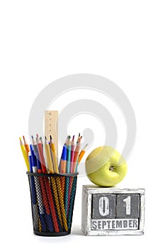 Green apple, organizer with pencils and ruler, stationery stand and calendar with date September 01.On white background.