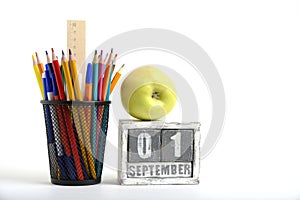 Green apple, organizer with pencils and ruler, stationery stand and calendar with date September 01.On white background.