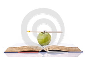 Green apple and pencil on book. Studio shot isolated on white