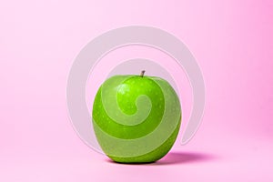 Green apple on a pink background. Glamor apple