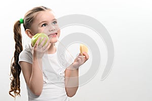 Green apple and potato chips, healthy and unhealthy food for kids, little girl chooses apple over chips.