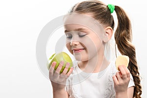 Green apple and potato chips, healthy and unhealthy food for kids, little girl chooses apple over chips.
