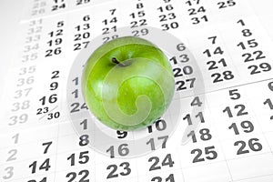 Green apple on sheets of wall calendar