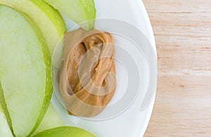 Green apple slices on dish with peanut butter table top