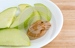 Green apple slices on dish with peanut butter table top