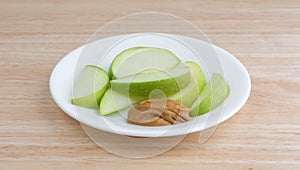 Green apple slices on dish with peanut butter table top