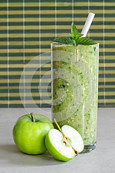 Green apple smoothie in a glass, whole and half apple