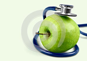 Green apple and a stethoscope on background