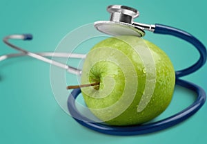 Green apple and a stethoscope on blue background