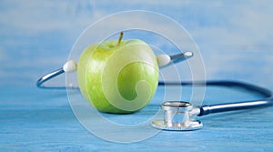 Green apple with stethoscope on the blue background