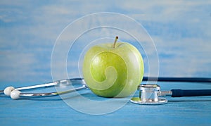 Green apple with stethoscope on the blue background