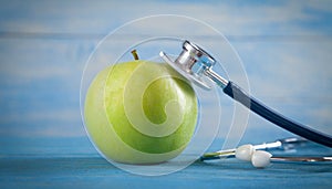 Green apple with stethoscope on the blue background