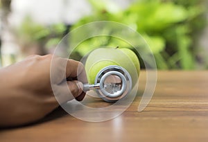 Green apple with stethoscope for health concept