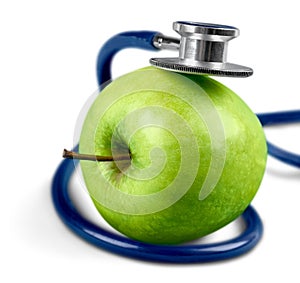 Green apple and a stethoscope on white background