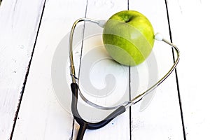 green apple with stethoscope on white wood table,Concept for diet, healthcare, nutrition or medical insurance.
