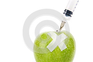 A green apple with a syringe stucked