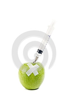 A green apple with a syringe stucked