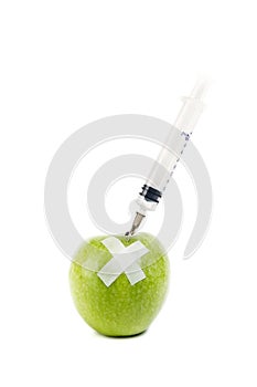 A green apple with a syringe stucked photo