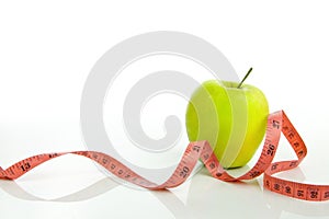 Green apple with tape measure on a white background