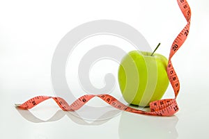 Green apple with tape measure on a white background