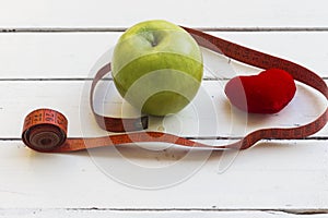 green apple with tape measure on white wood table,Concept for diet, healthcare, nutrition or medical insurance.