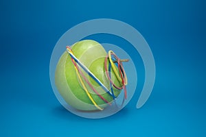 Green apple tied in colorful rubber bands