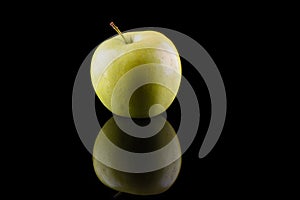 Green apple variety Golden on a black background with reflection