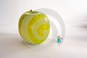 Green apple or vitamin pills on a white background. Healthy eating, diet, lifestyle concept, treatment choice concept