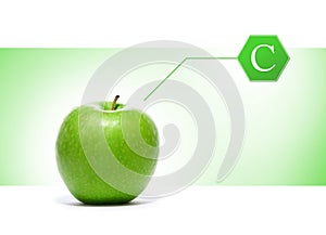 A green apple with a vitamin sign on a light background