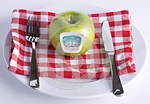 Green apple on a white plate with knife and fork