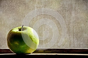 Green apple on a wood window frame