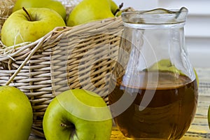 Green apples, basket with apples and jug with apple juice on wooden background