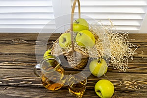 Green apples, basket with apples and jug with apple juice on wooden background