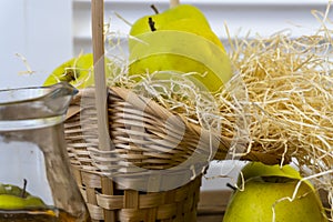 Green apples, basket with apples and jug with apple juice on wooden background