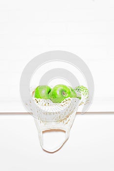 Green apples in beige eco mesh bag.