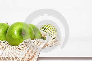 Green apples in beige eco mesh bag.