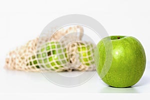 Green apples in beige eco mesh bag.