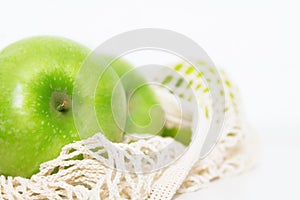 Green apples in beige eco mesh bag.