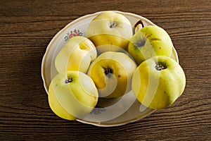 Green apples in a white plate on a table