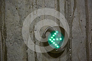 Green arrow as directional sign in LED lights on a concrete wall