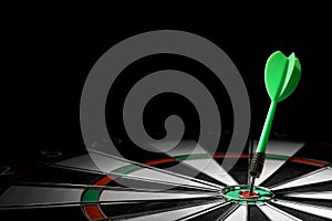 Green arrow hitting target on dart board against black background