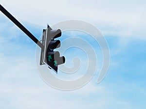 Green arrow symbol on traffic light against blue sky