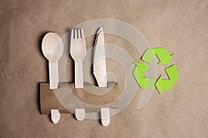 Green arrows recycle symbol with with bamboo cutlery on brown paper background