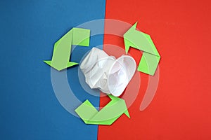 Green arrows recycle it symbol on a blue and red background. recycled material symbol. Used crumpled white disposable glass