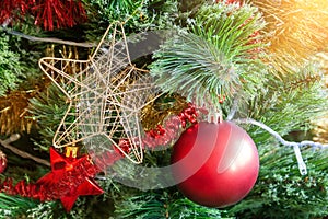 Green artificial Christmas tree decorated with star in a golden frame; red matte ball; and yellow and red garlands