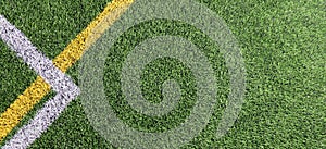 Green artificial grass turf soccer football field background with white and yellow line boundary. Top view