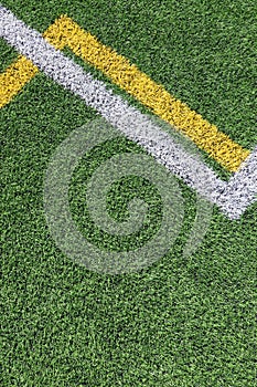 Green artificial grass turf soccer football field background with white and yellow line boundary. Top view