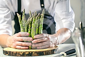 Green asparagus kept in men`s Chef cook hands