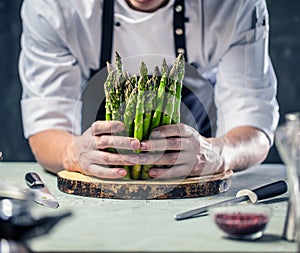 Green asparagus kept in men`s Chef cook hands