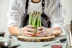 Green asparagus kept in men`s Chef cook hands